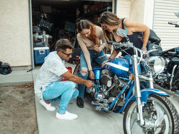 Mechanic in workshop examining motorcycle engine with tools laid out on a workbench
