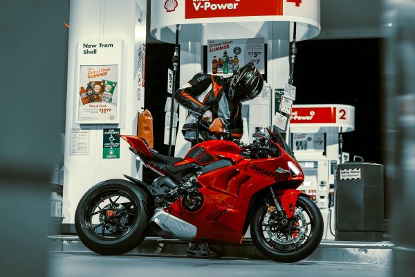 Motorcycle rider at a fuel station checking mileage before filling the tank